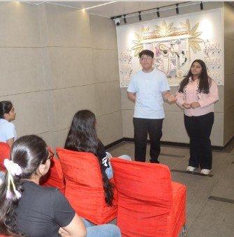 Two presenters speaking to a seated audience during an indoor masterclass